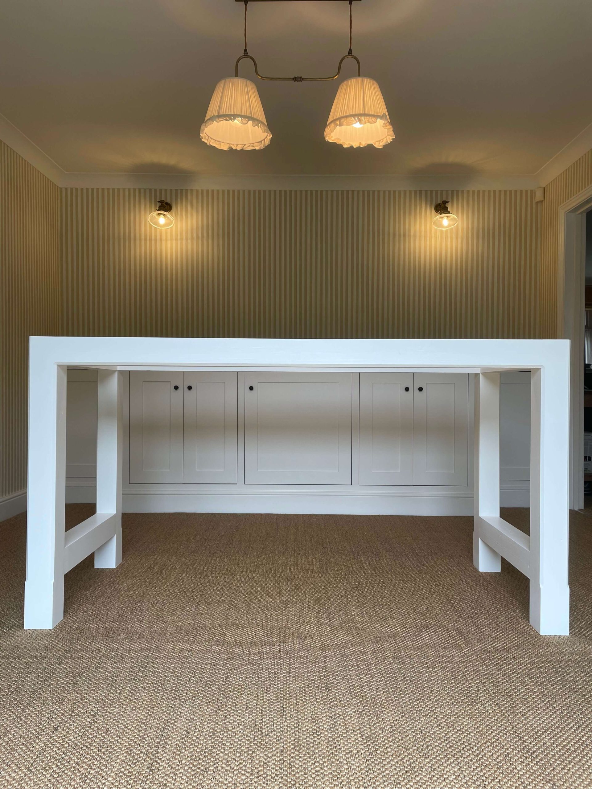 Painted breakfast bar with a built-in cupboard run behind, under twin pendant lights