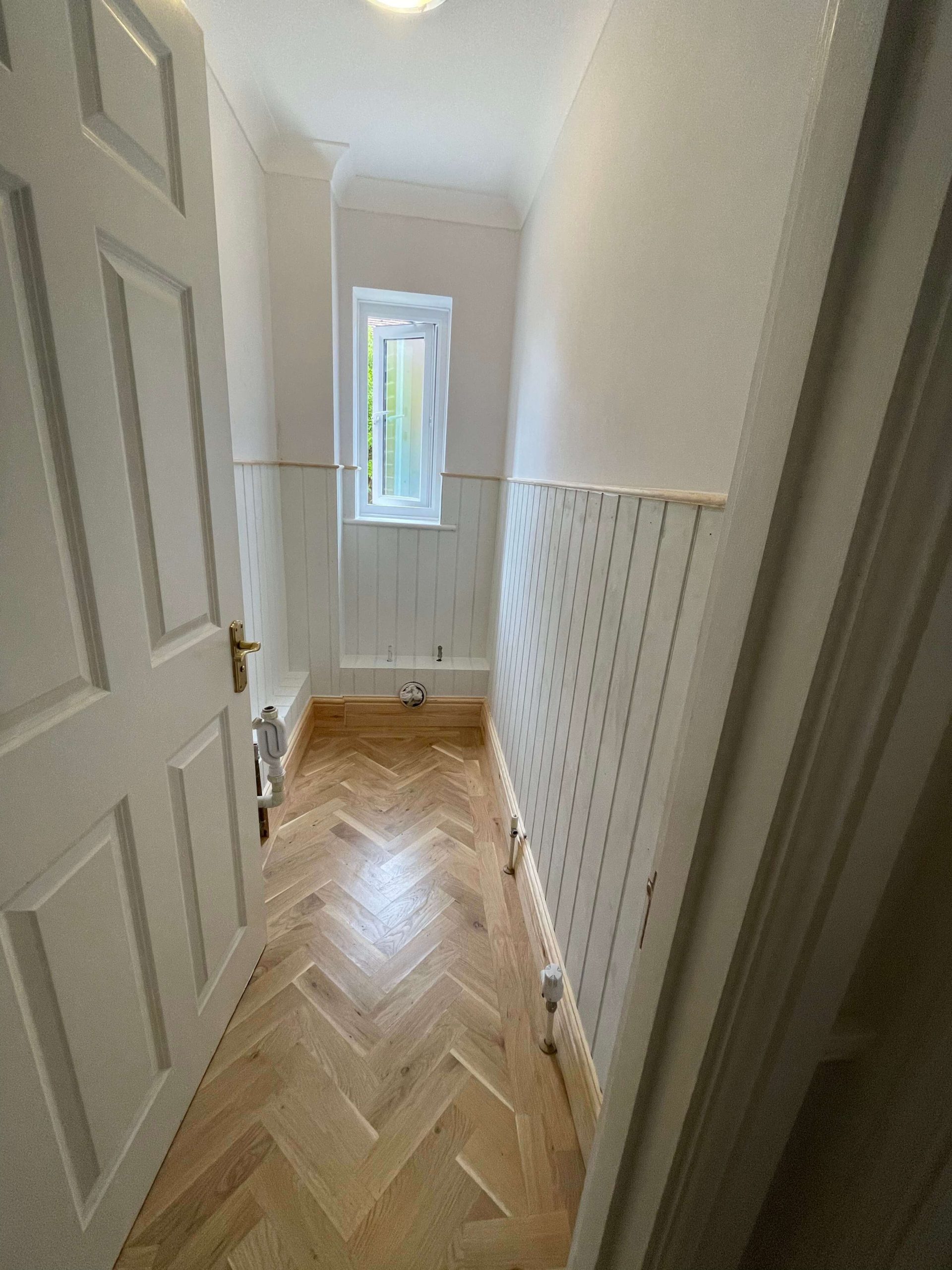 Hallway with an oak plank door set into an exposed timber frame, with oak flooring and skirting