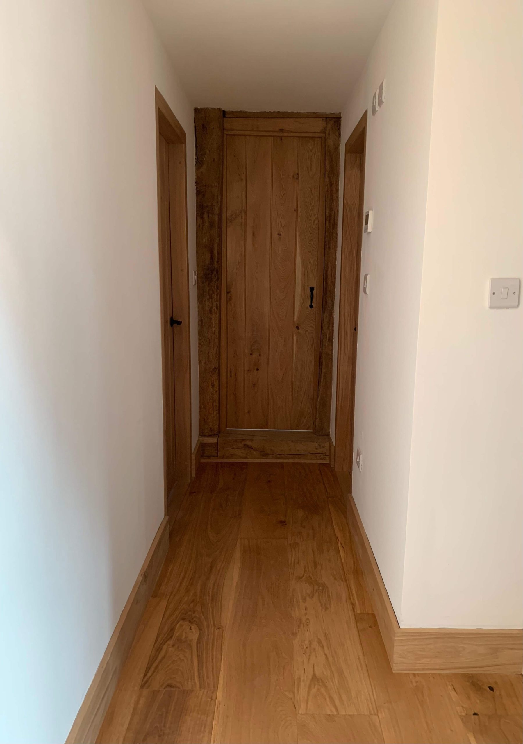 Solid oak ledged door with black ironmongery in a matching oak frame