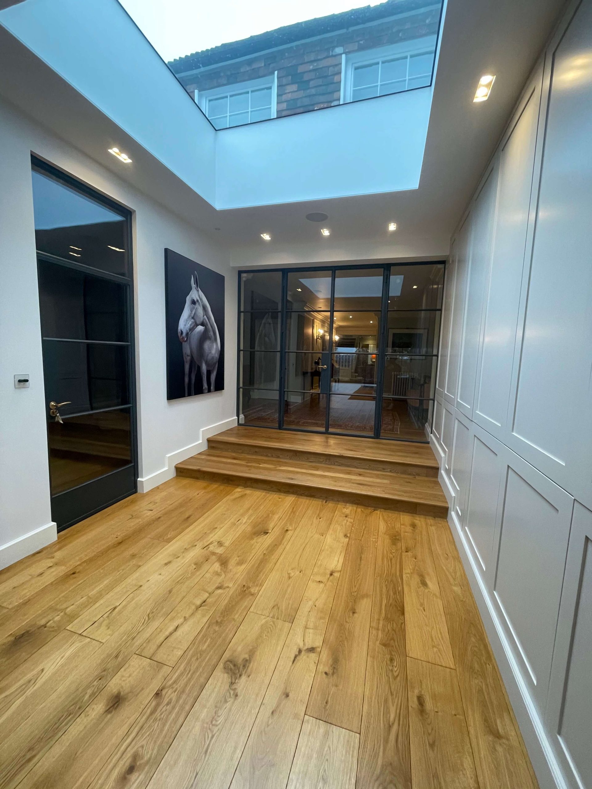 Hallway with a roof lantern, steel-framed glazed doors and wide oak floorboards
