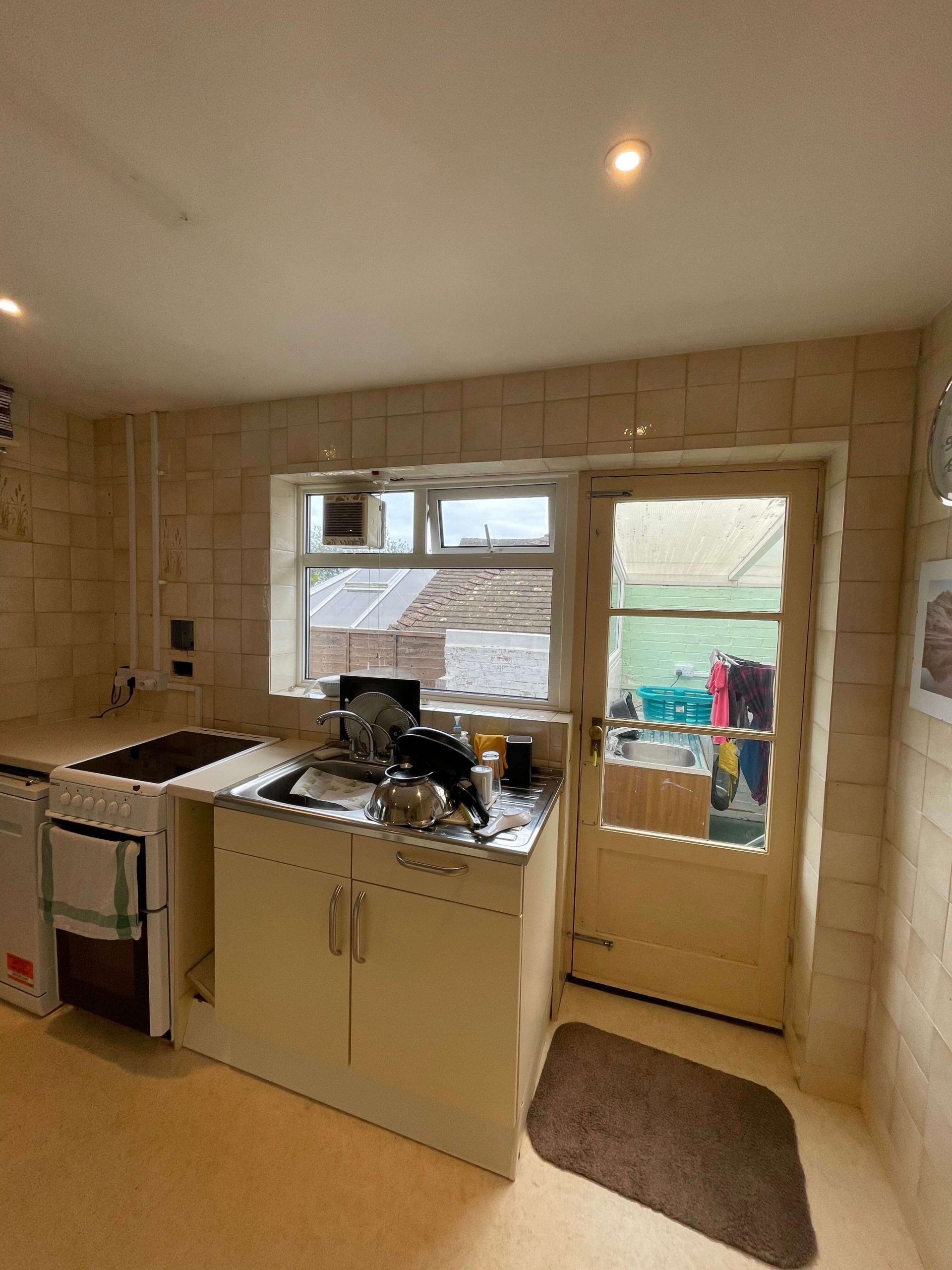 Kitchen before refurbishment, with dated wall tiling and original fitted units