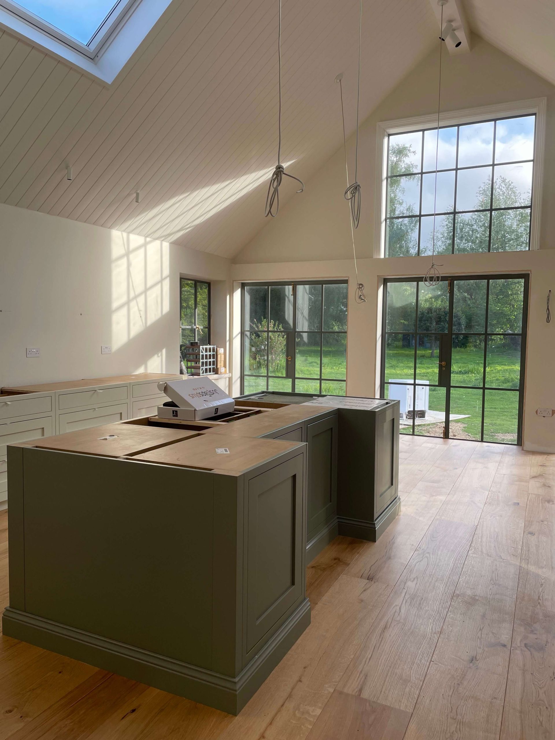 Open-plan kitchen with vaulted panelled ceiling, steel-framed garden doors and a green painted island