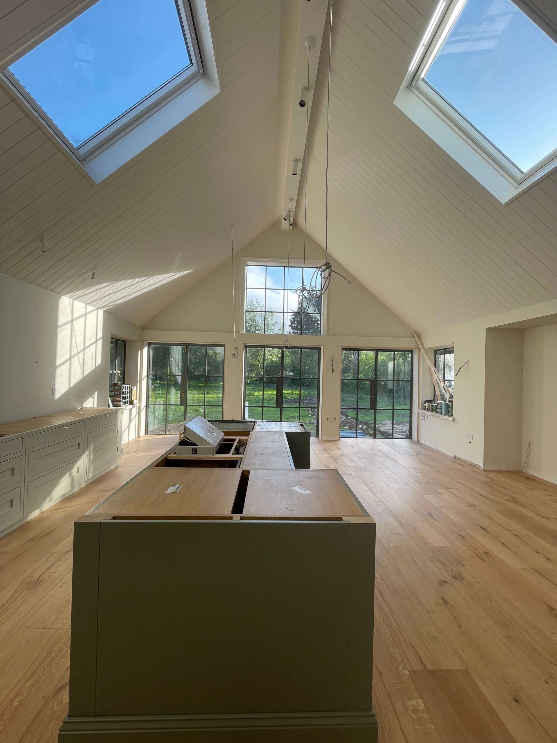 Vaulted room with panelled ceiling, roof light and full-height glazing overlooking the garden